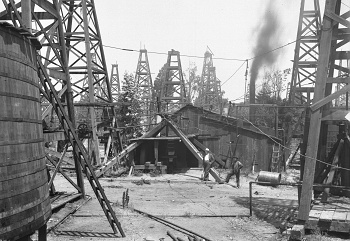 Two_men_standing_near_a_wooden_shed_in_the_midst_of_dozens_of_oil_derricks_in_a_Los_Angeles_oil_field_1